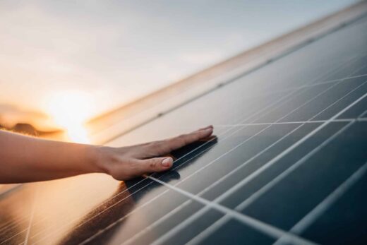 La main touche le panneau solaire au coucher du soleil.