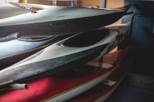 Kayaks empilés utilisés dans un garage sombre.