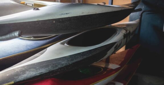 Kayaks empilés utilisés dans un garage sombre.