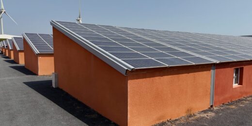 Bâtiments orange avec panneaux solaires et éoliennes.