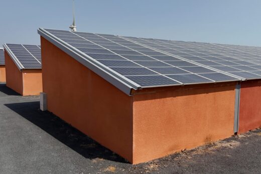 Bâtiments orange avec panneaux solaires et éoliennes.