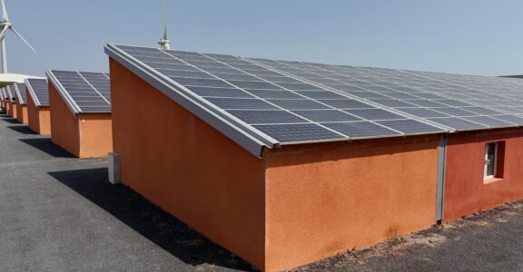 Bâtiments orange avec panneaux solaires et éoliennes.
